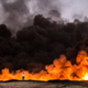 A man stands in front of a fire from oil that has been set ablaze in the Qayyarah area of Iraq.